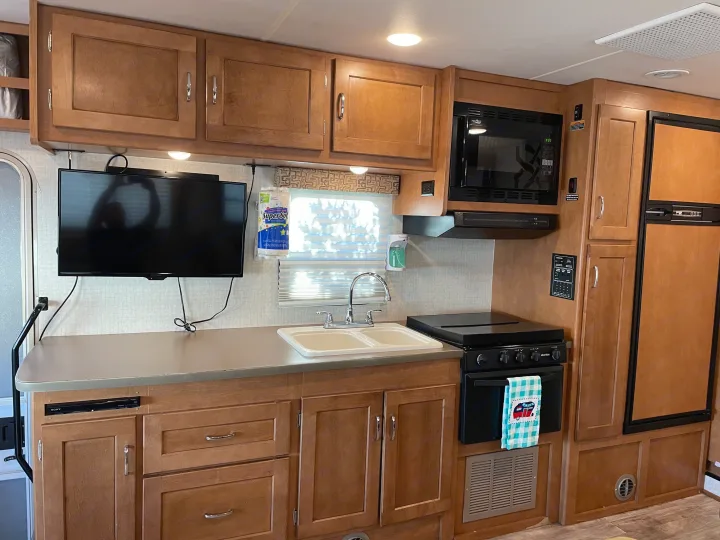 Kitchen space includes TV, DVD player, microwave, stove, refrigerator, and ample kitchen cabinets. Winnebago Minnie Winnie 2017