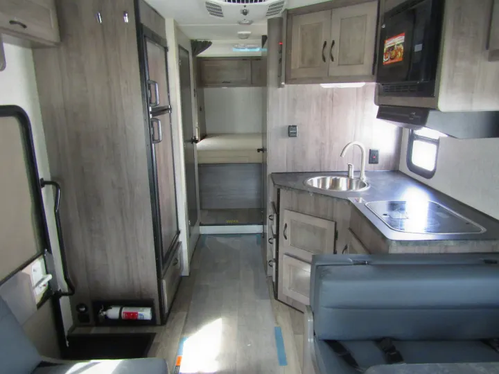 Spacious RV rental interior showcasing a kitchen with sink, stove, refrigerator, seating, and a rear bedroom.. Winnebago Minnie Winnie 2020