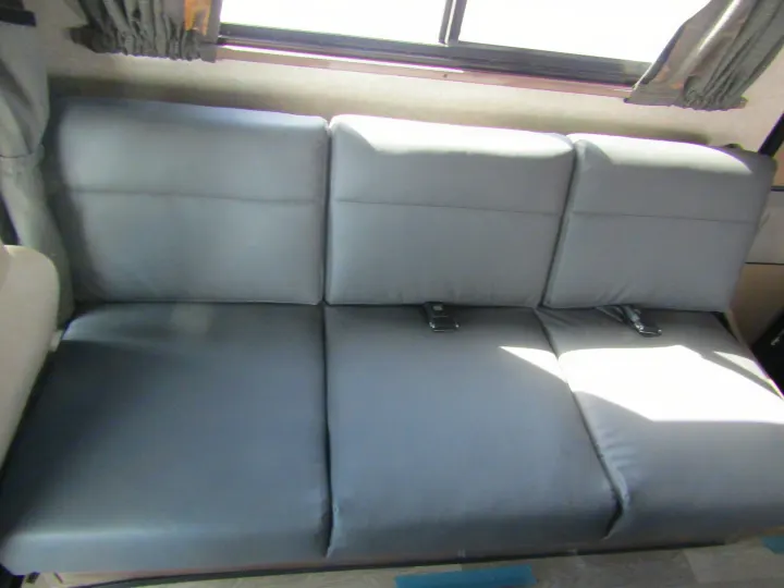 RV rental interior showing a gray three-person bench seat with seatbelts under a window.. Winnebago Minnie Winnie 2020