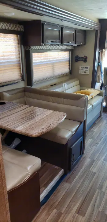 RV rental: Modern interior featuring a light U-shaped dinette with wood-grain table, a sofa, and dark overhead cabinets.. Thor Motor Coach 30.3 2019