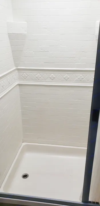RV rental shower: white tiled walls, decorative trim, corner shelf, and off-white shower pan with minor reddish stains.. Thor Motor Coach 30.3 2019