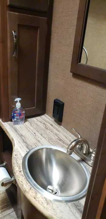 RV rental bathroom featuring a compact stainless steel sink, faucet, hand soap, and toilet paper holder. Efficient design.. Thor Motor Coach 30.3 2019