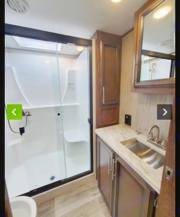 Spacious RV rental bathroom featuring a glass shower with skylight and seat, vanity with sink, mirror, and ample storage cabinets.. KZ Recreational Vehicles Durango 2021