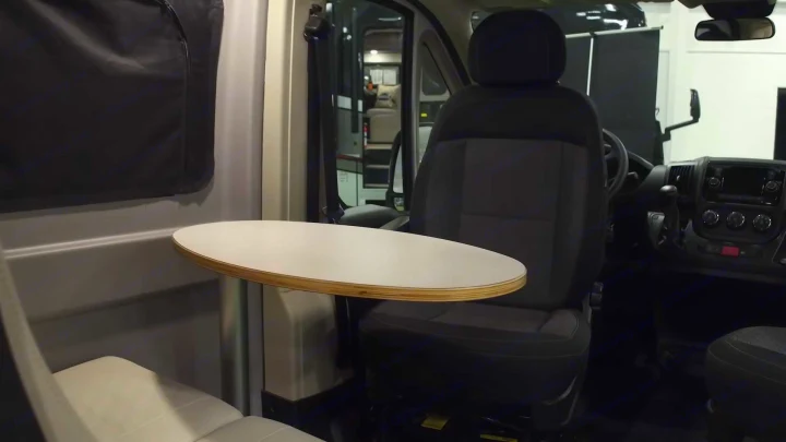 Compact RV rental interior featuring a small table, comfortable seating, and dashboard view, ideal for travel.. Winnebago Solis 2021