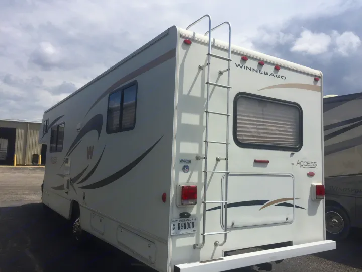 White Winnebago Access RV rental parked outside, showing its rear with a ladder and Indiana license plate.. Winnebago Access 2007