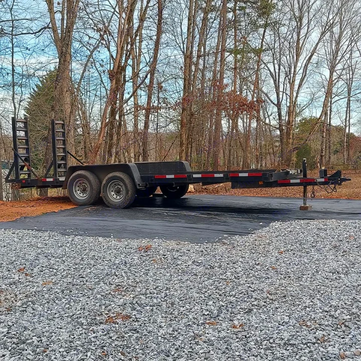 Black dual-axle utility trailer with ramps, ideal for heavy equipment or RV rental transport. Parked on a dark ground cover.. Currahee SS 720 14K 2016