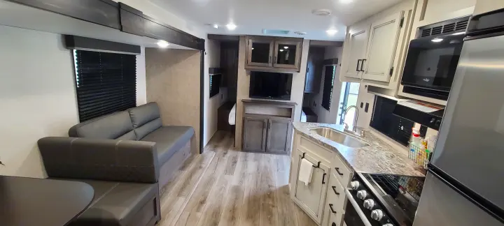 Spacious and modern RV rental interior featuring a full kitchen, living area with a sofa, and dining space for comfortable travel.. Open Range 26BHS 2021