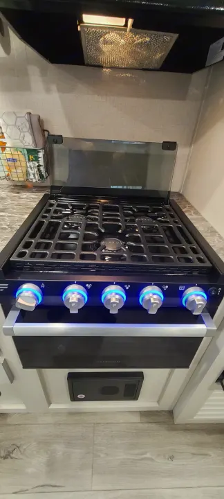 RV rental: A modern kitchen stove/oven with bright blue illuminated control knobs and a clear glass cover.. Open Range 26BHS 2021