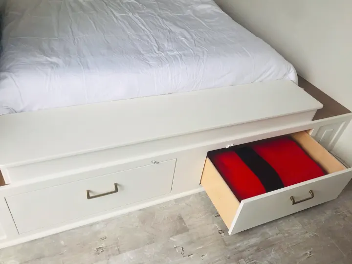 White storage bed with open drawer revealing red items, a practical bedroom solution for RV rental.. Custom Camper Trailer 2020