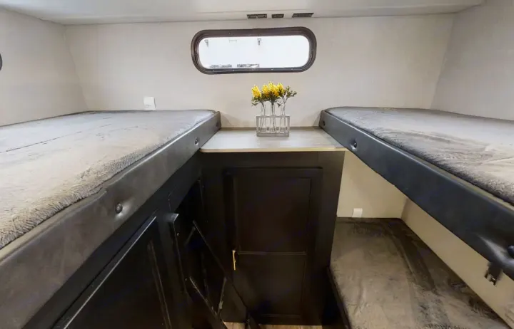 This RV rental offers a compact bunk bed area, complete with upper and lower bunks, a central table, and a window.. Forest River Grey Wolf 29te 2021