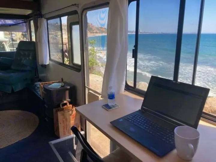 Inside an RV rental, a laptop desk by large windows overlooks a stunning ocean. Perfect mobile office for remote work.. Safari Trek 2610 1994