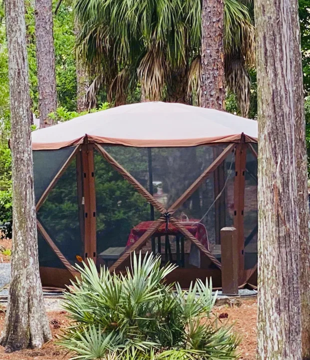 Cozy screen tent setup at an RV rental site, offering shaded outdoor living amidst lush trees.. Keystone Hideout 2016