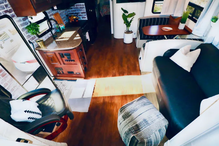 Cozy, modern RV rental interior featuring a full kitchen with brick backsplash, dining area, and comfortable living space with wood floors.. Jayco Seneca 2013