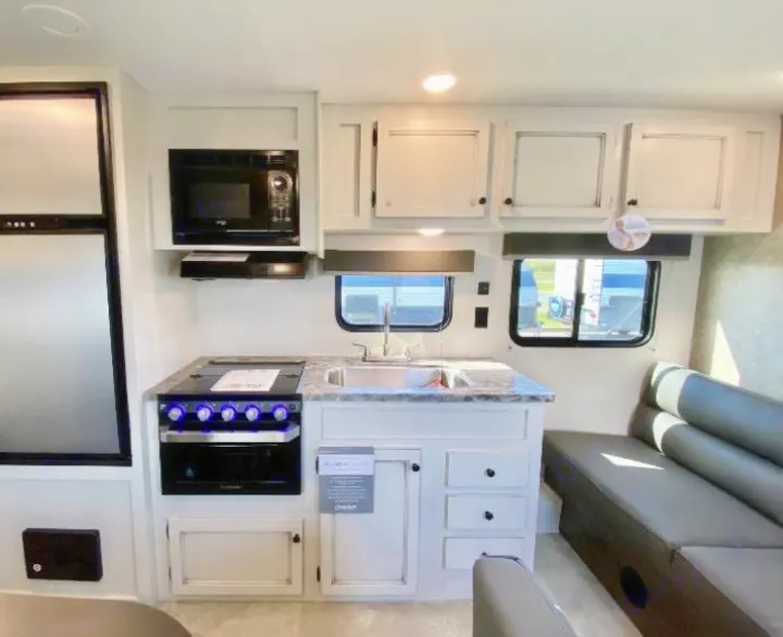 RV rental interior showcasing a modern kitchen with stove, microwave, fridge, sink, and an inviting living area sofa.. Highland Ridge RV Open Range 2021