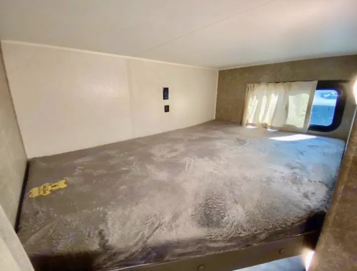 Cozy RV rental bunk bed area with soft grey bedding, window, & outlets for a comfortable travel stay.. Highland Ridge RV Open Range 2021