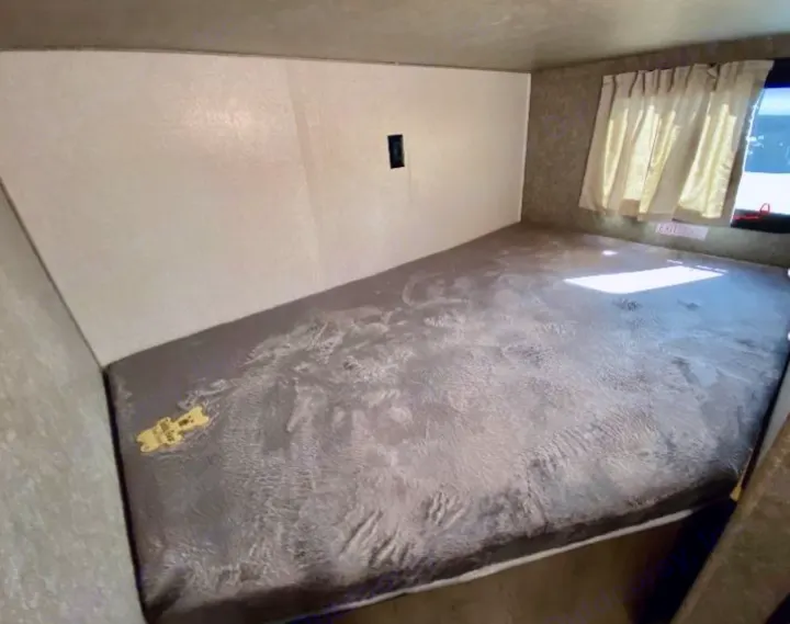 RV rental interior: spacious grey sleeping area, window with curtains, and an exit sign. Ready for your adventure.. Highland Ridge RV Open Range 2021