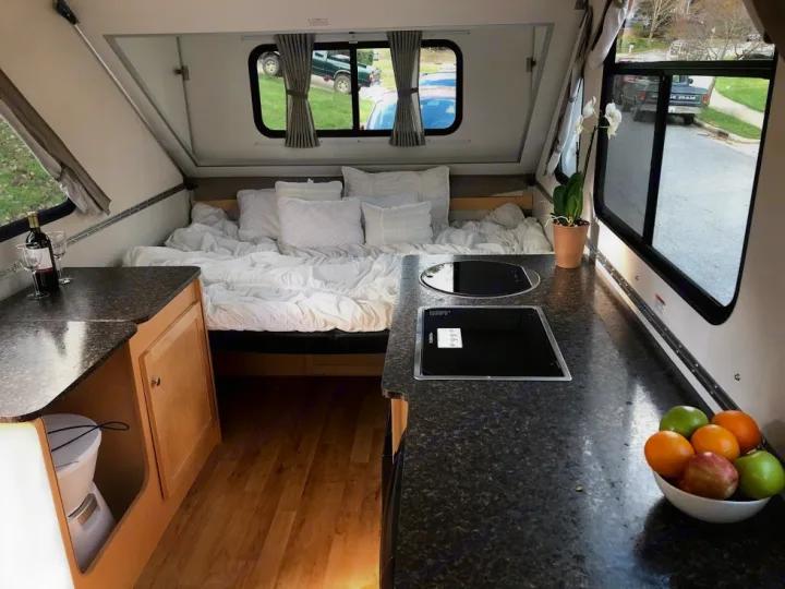 Explore this A-frame RV rental's cozy interior, featuring a full bed, modern kitchen, and convenient counter space for travel adventures.. A-Liner Expedition 2021
