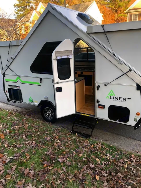 A gray A-Liner A-frame camper RV rental with its door open, revealing a compact interior with steps.. A-Liner Expedition 2021