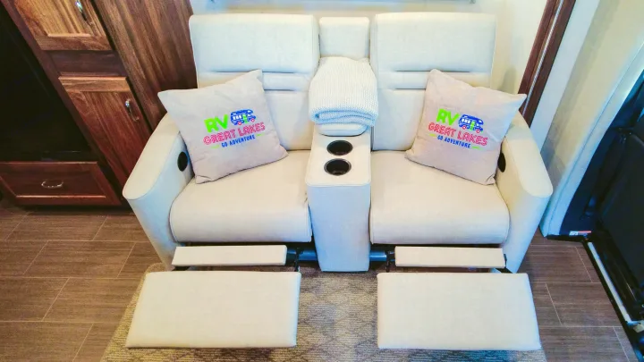 Comfortable RV rental interior with extended recliners, central console with cupholders, and custom RV logo pillows.. Winnebago Vita 2020