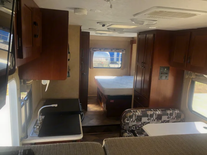 An RV rental's inviting interior features a functional kitchen, comfortable bed, and versatile dining space.. Forest River Sunseeker 2014