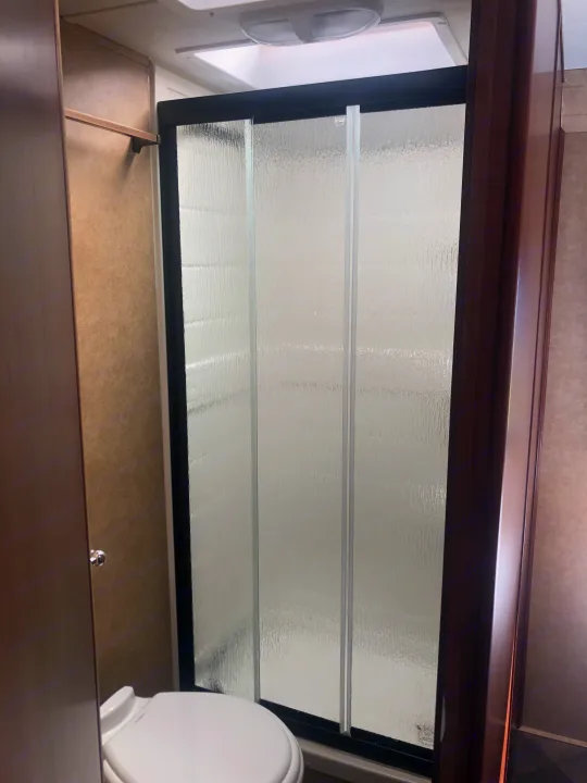 RV rental bathroom interior: Textured glass shower, toilet, and vanity space.. Forest River Sunseeker 2014