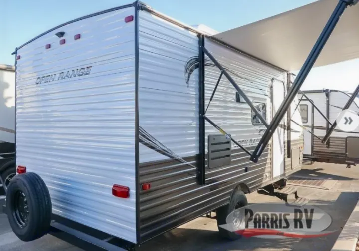 Explore the outdoors with this white & black travel trailer RV rental, featuring an extended awning and spare tire.. Highland Ridge RV Open Range 2021
