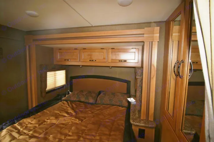 Cozy RV rental bedroom featuring a full bed, overhead storage cabinets, and a mirrored wardrobe, perfect for comfortable travel.. Thor Motor Coach Freedom Elite 22FE 2017