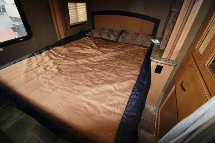 Explore a comfortable RV rental bedroom, featuring a neatly made bed, nightstand, and window. Your private retreat on the road.. Thor Motor Coach Freedom Elite 22FE 2017