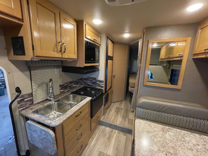 This RV rental interior features a full kitchen with sink, stove, microwave, and a cozy dinette area.. Thor Motor Coach Freedom Elite 22FE 2017
