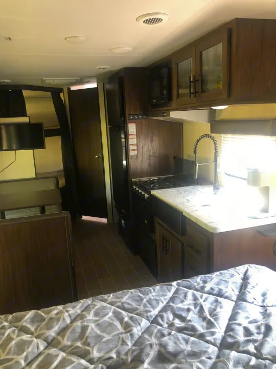 Bright RV rental interior: kitchen with modern appliances, bunk beds, and cozy main sleeping area shown.. Forest River Cherokee Grey Wolf 22MKSE 2020