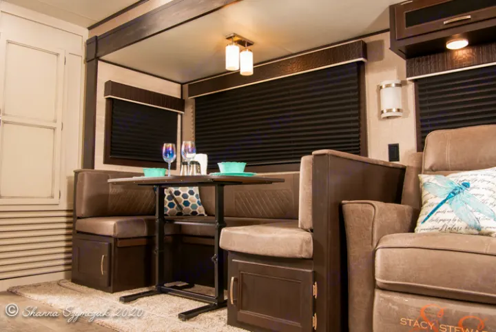 RV rental interior: cozy dinette with dark wood table & booth seating, next to a comfy light gray recliner.. Jayco Jay Flight 2021