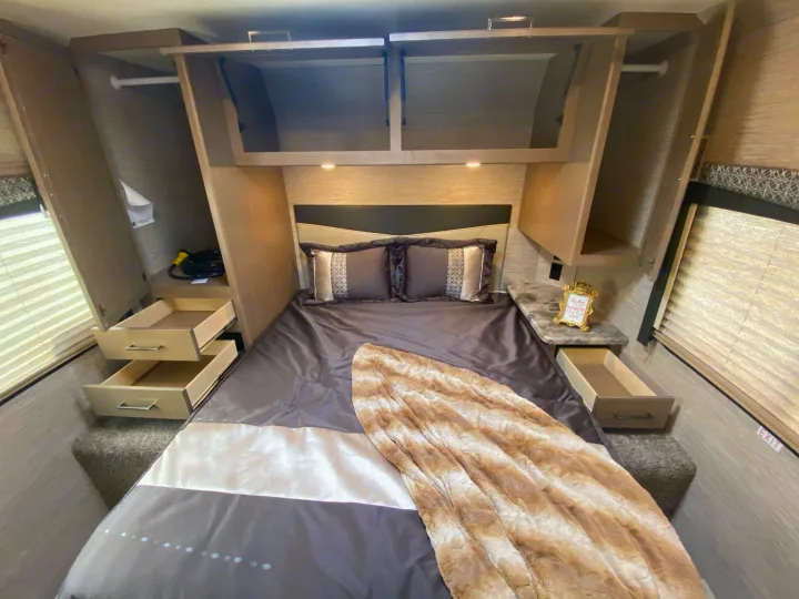 Cozy RV rental bedroom with ample storage: overhead cabinets, wardrobe, and built-in bed drawers.. Other Four Winds 2021