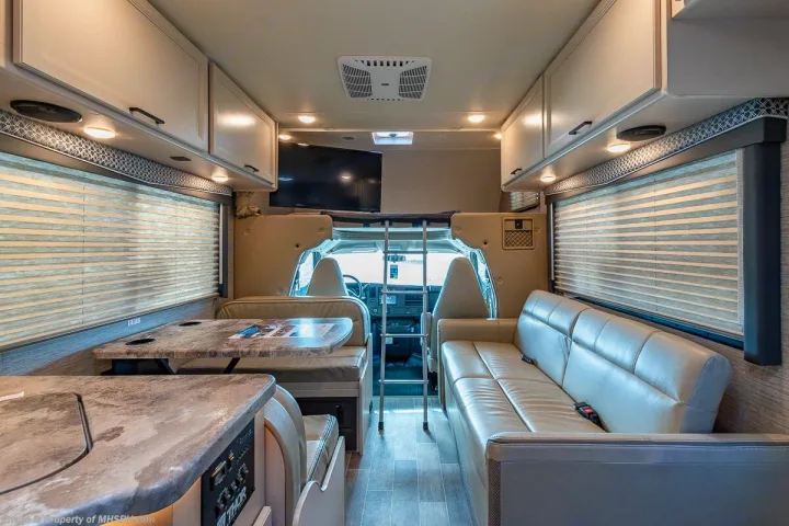 Spacious RV rental interior featuring dining, living areas, and overhead bunk with TV for comfortable travel.. Other Four Winds 2021