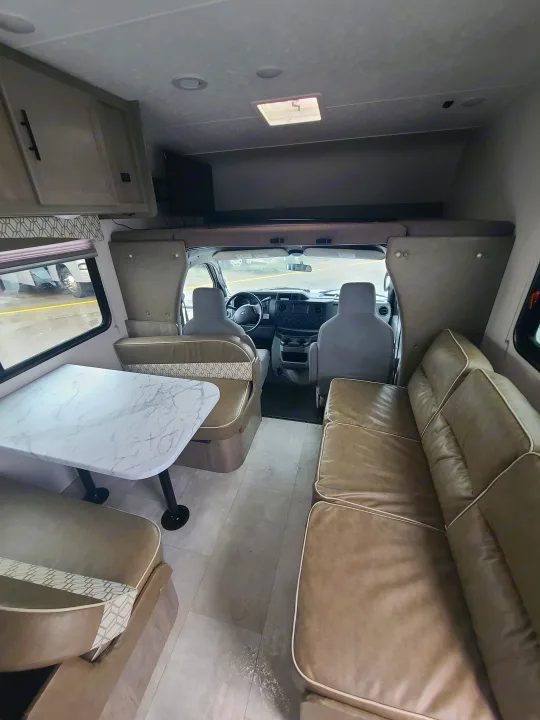 Spacious RV rental interior with dinette, sofa, overhead bunk, and cockpit, perfect for travel.. Coachmen Freelander 2021