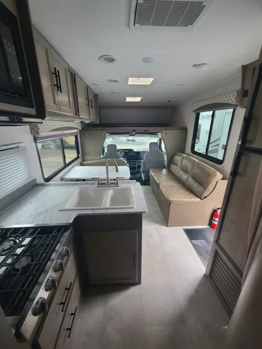 Spacious RV rental interior showcasing a full kitchen, dining table, and cozy living area.. Coachmen Freelander 2021