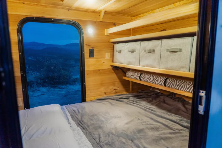 Cozy RV rental bedroom with a large window offering nature views, practical wooden shelves, and organized storage bins.. PINNACLE Pinnacle Summit 2020