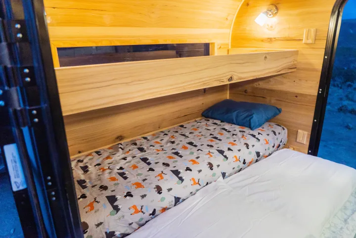 Cozy wooden RV rental interior with bunk beds. The lower bed features a forest animal sheet & blue pillow.. PINNACLE Pinnacle Summit 2020