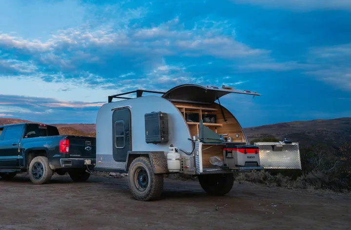 Adventure-ready RV rental: A pickup truck tows a teardrop trailer with an open outdoor kitchen, perfect for remote camping.. PINNACLE Pinnacle Summit 2020