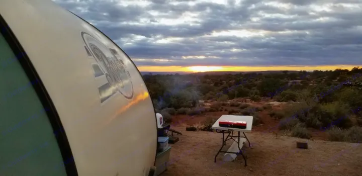 Experience a serene desert sunset from your RV rental campsite, featuring a small trailer & cooking table.. Other Other 2016