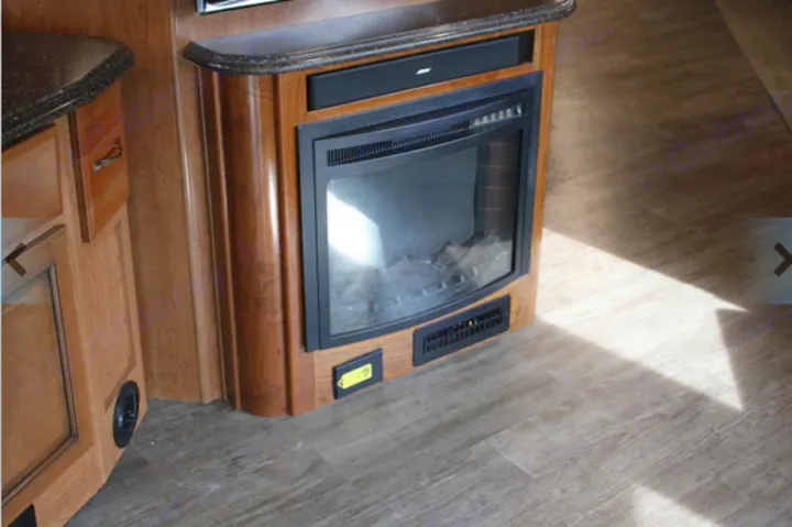RV rental interior showing a wood cabinet with an electric fireplace, a Bose soundbar, and light wood-look flooring.. Fleetwood Pace Arrow 2018