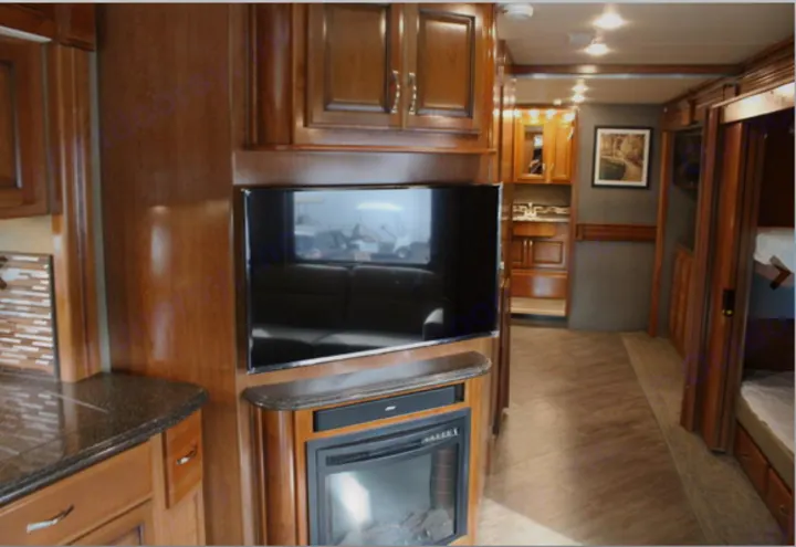 Interior of a luxurious RV rental with wood cabinetry, a large TV, fireplace, kitchen & bathroom.. Fleetwood Pace Arrow 2018