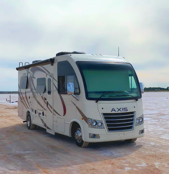 This rv rental, a white Axis motorhome, is parked on a unique reddish salt flat under a pale sky, ready for adventure.. Thor Motor Coach Axis 2018