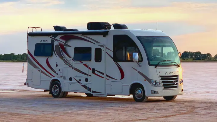 Sleek Axis RV rental parked on a vast, flat landscape under a soft sky. Your perfect motorhome for outdoor adventures.. Thor Motor Coach Axis 2018