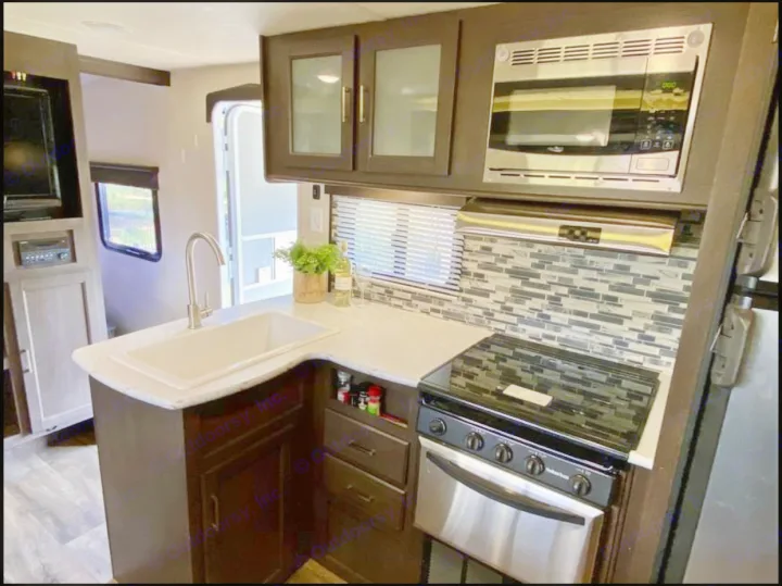 This kitchen has a four burner stove, microwave, oven, place settings for 6, pot/pans, and basic cookware. . Forest River Wildwood X-Lite 2018
