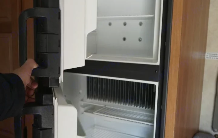 Opening an RV rental's fridge, showing the empty freezer and refrigerator compartments ready for use.. Thor Motor Coach Four Winds Majestic 2013