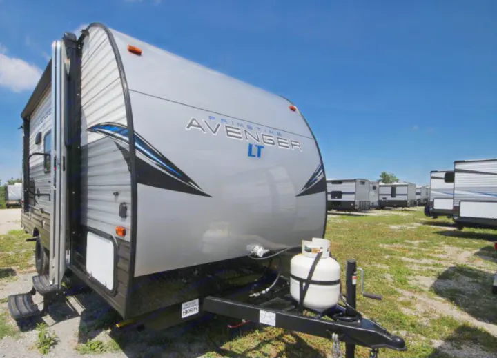 Front view of a gray Prime Time Avenger LT travel trailer, equipped with propane tanks, ideal for an rv rental.. Prime Time Avenger 2021