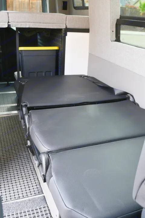 RV rental interior: modular black leather seats/bed, upper bunk, and storage. Ideal flexible living space.. Storyteller Overland Storyteller Overland Class B 2021