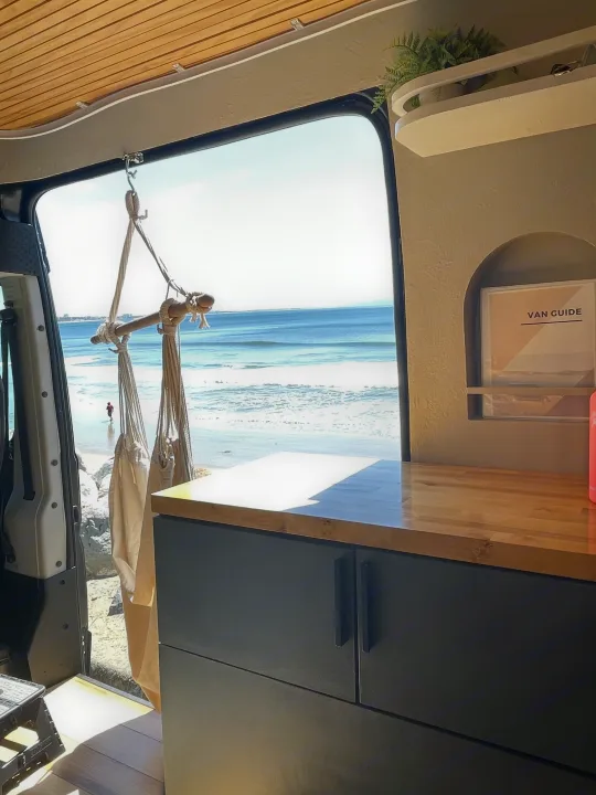 RV rental: Bright camper van interior with wooden ceiling & counter, custom storage, offering a clear beach and ocean view.. Other Other 2015