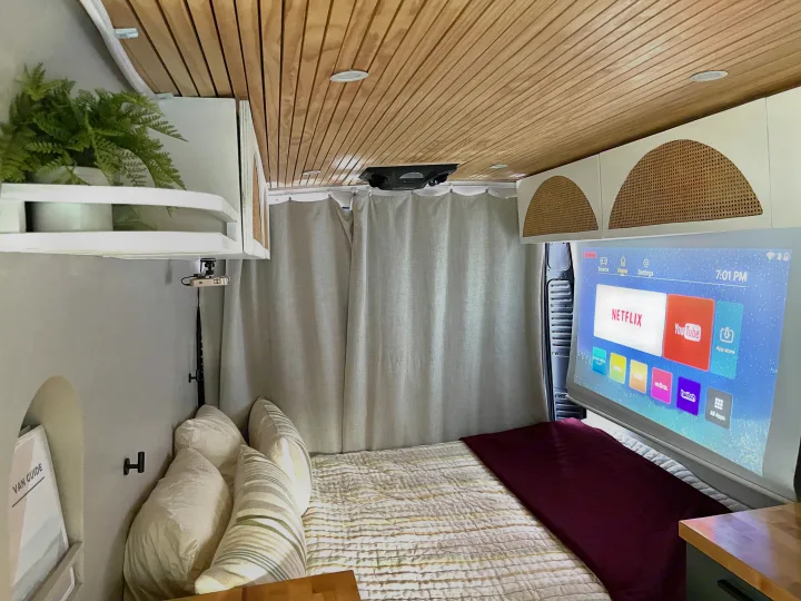 Inside a modern rv rental: a cozy sleeping area with a projector casting smart apps like Netflix & YouTube onto a screen.. Other Other 2015