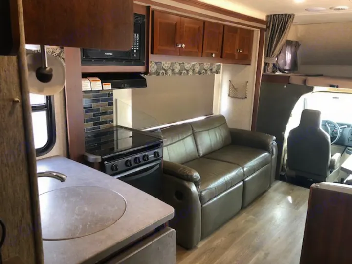 Experience comfortable travel in this RV rental's inviting interior: full kitchen, cozy sofa, and driver's cabin.. Forest River Sunseeker 2017